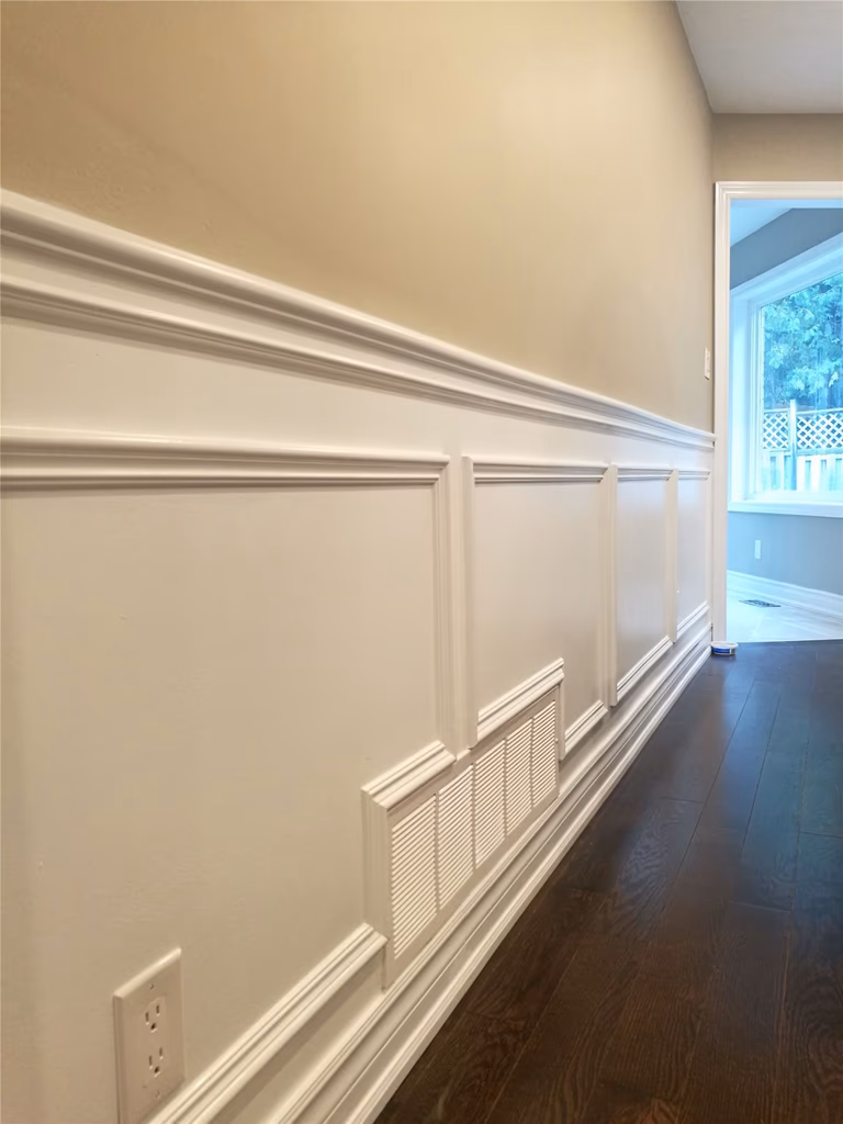 This Newmarket interior renovation features custom wall paneling and wainscoting with clean trim lines and precise detailing. Paired with dark hardwood flooring, the refined wall finish adds depth and elegance to the space, highlighting the craftsmanship and finish quality delivered by a professional Toronto renovation company.