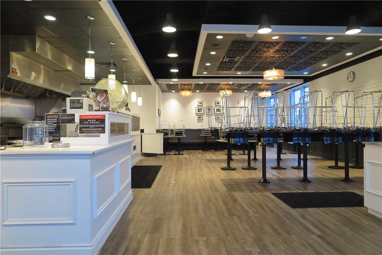 This Toronto restaurant renovation highlights the upgraded front service counter and customer-facing area completed by Reno Compass Inc. The project included custom-built cashier counters, integrated POS stations, decorative ceiling bulkheads with recessed lighting, and commercial-grade pendant fixtures to enhance ambiance and visibility.

The open layout improves customer flow and ordering efficiency, while durable vinyl flooring ensures long-term performance in high-traffic commercial environments. The refined white counter millwork contrasts with the modern dark ceiling design, creating a clean yet contemporary restaurant atmosphere.

As an experienced Toronto renovation company, Reno Compass Inc. specializes in restaurant interior renovations that balance operational functionality with strong visual branding.