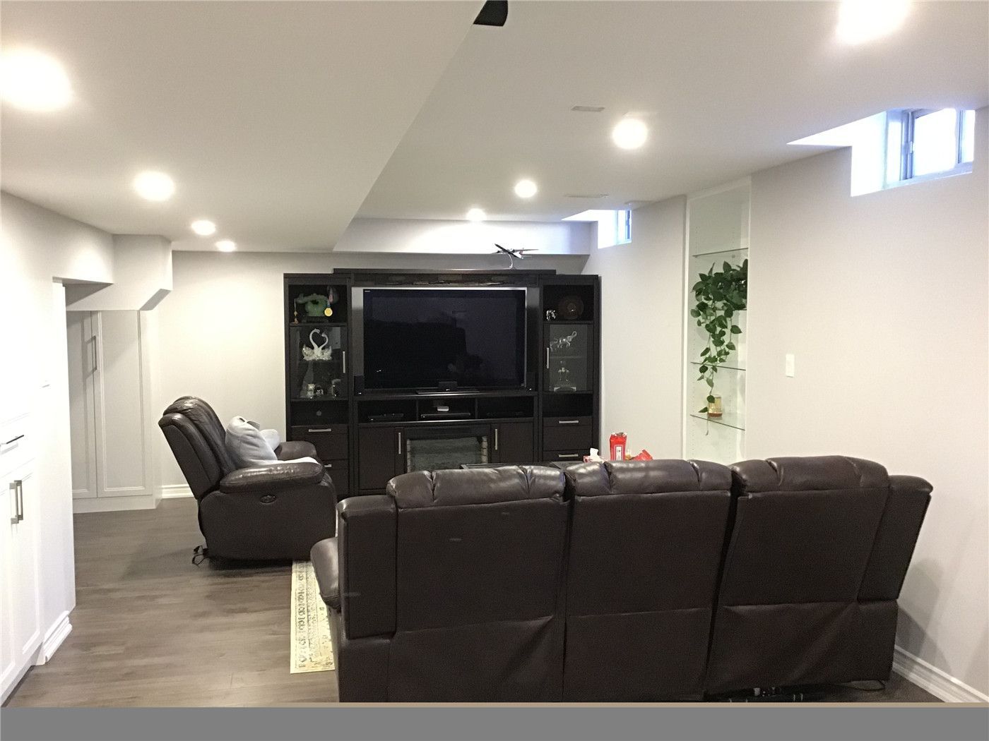 Finished basement renovation in Aurora showcasing a custom home theater setup with built-in media cabinetry, recessed pot lights, and modern vinyl plank flooring. The open-concept layout maximizes comfort and functionality, creating a perfect family entertainment space. Completed by a professional Toronto renovation company with attention to lighting, space planning, and high-end finishes.
