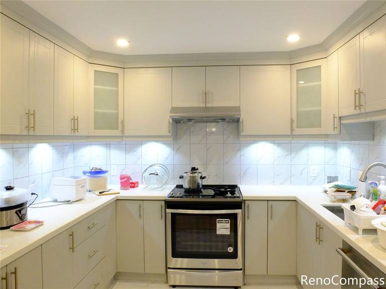 This Aurora kitchen renovation features elegant custom white cabinetry with gold hardware, a marble-style backsplash, and modern recessed lighting. The upgraded layout improves functionality while creating a bright and sophisticated cooking space. Completed with clean countertop finishes and integrated under-cabinet lighting, this renovation reflects the quality craftsmanship and attention to detail delivered by Reno Compass Inc., a trusted Toronto renovation company serving Aurora and the Greater Toronto Area.
