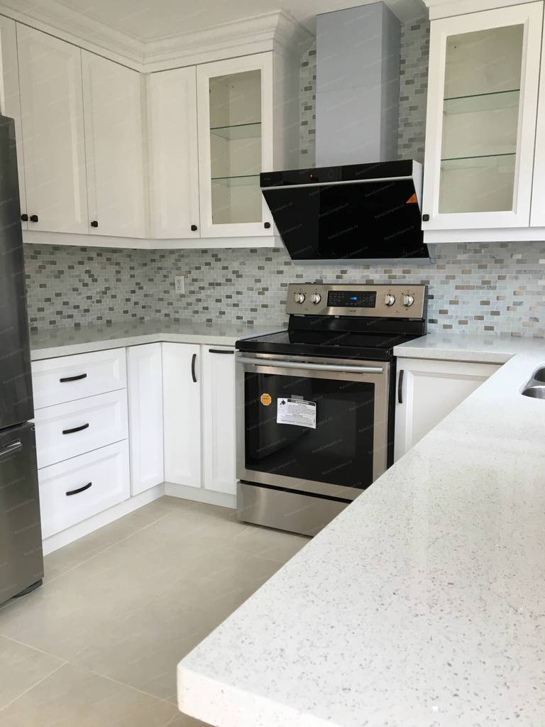 This Markham interior renovation features a bright modern kitchen upgrade with white shaker cabinets, quartz countertops, stainless steel appliances, and contemporary backsplash tile. Completed by a professional Toronto renovation company, the space was redesigned to improve functionality, storage, and overall flow while maintaining a clean, timeless aesthetic.