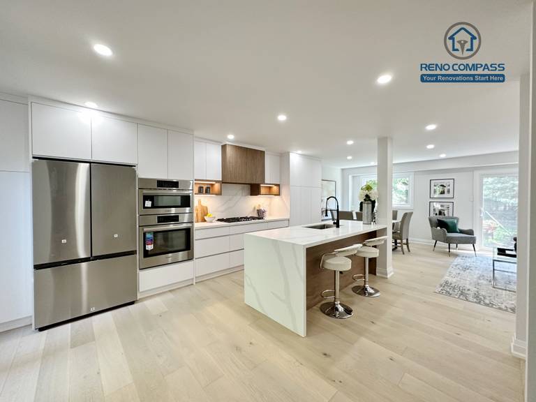 This Richmond Hill interior renovation features a bright open-concept kitchen and living space with custom white cabinetry, integrated stainless steel appliances, a waterfall kitchen island, and wide-plank hardwood flooring. Designed and completed by a Toronto renovation company, the layout enhances natural light, functionality, and modern living comfort for contemporary family homes.