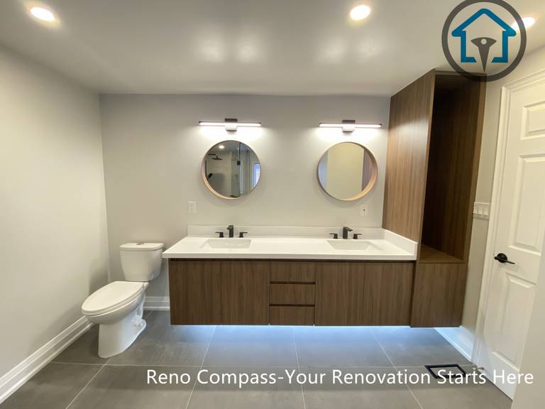Modern bathroom renovation in Markham featuring a floating wood vanity with double sinks, round mirrors, integrated LED lighting, and a clean minimalist layout. This project showcases functional storage, soft neutral tones, and a contemporary design completed by a professional Toronto renovation company.