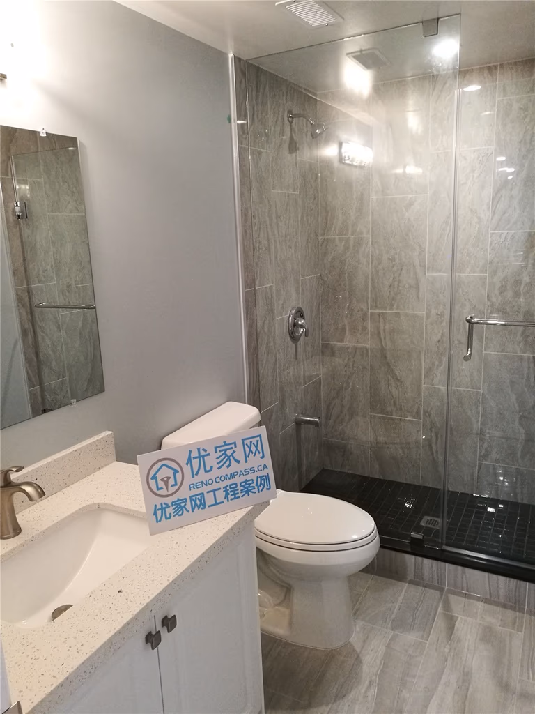 This image showcases a modern basement bathroom completed as part of a North York interior renovation. The space features a glass-enclosed shower, large-format tile finishes, a contemporary vanity, and clean plumbing fixtures. Neutral tones and durable materials enhance both functionality and visual appeal, creating a practical and comfortable bathroom design. This renovation reflects the quality workmanship of a professional Toronto renovation company serving the North York area.