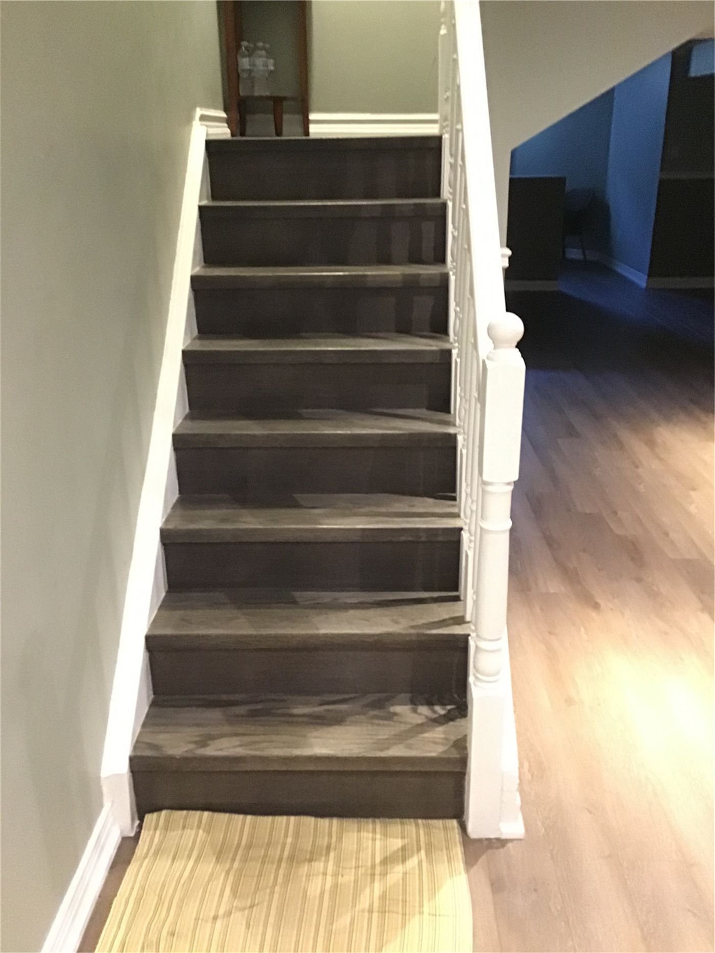 Professional staircase renovation in Markham. This project features premium dark wood stained treads, white painted risers, and classic white spindles for a high-contrast, modern aesthetic.