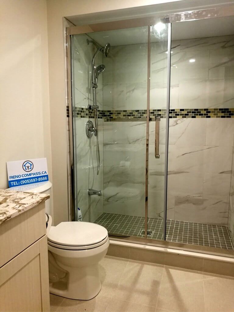 This Markham basement renovation features a fully upgraded bathroom with a sleek glass-enclosed shower and contemporary tile finishes. The space includes a walk-in shower with sliding glass doors, modern rainfall fixtures, mosaic accent tiles, and durable floor tiling designed for moisture resistance. The clean layout and neutral color palette create a bright, comfortable environment that complements the finished basement living space. Completed by a trusted Toronto renovation company, this basement bathroom renovation combines practicality, style, and long-term durability for modern family use.
