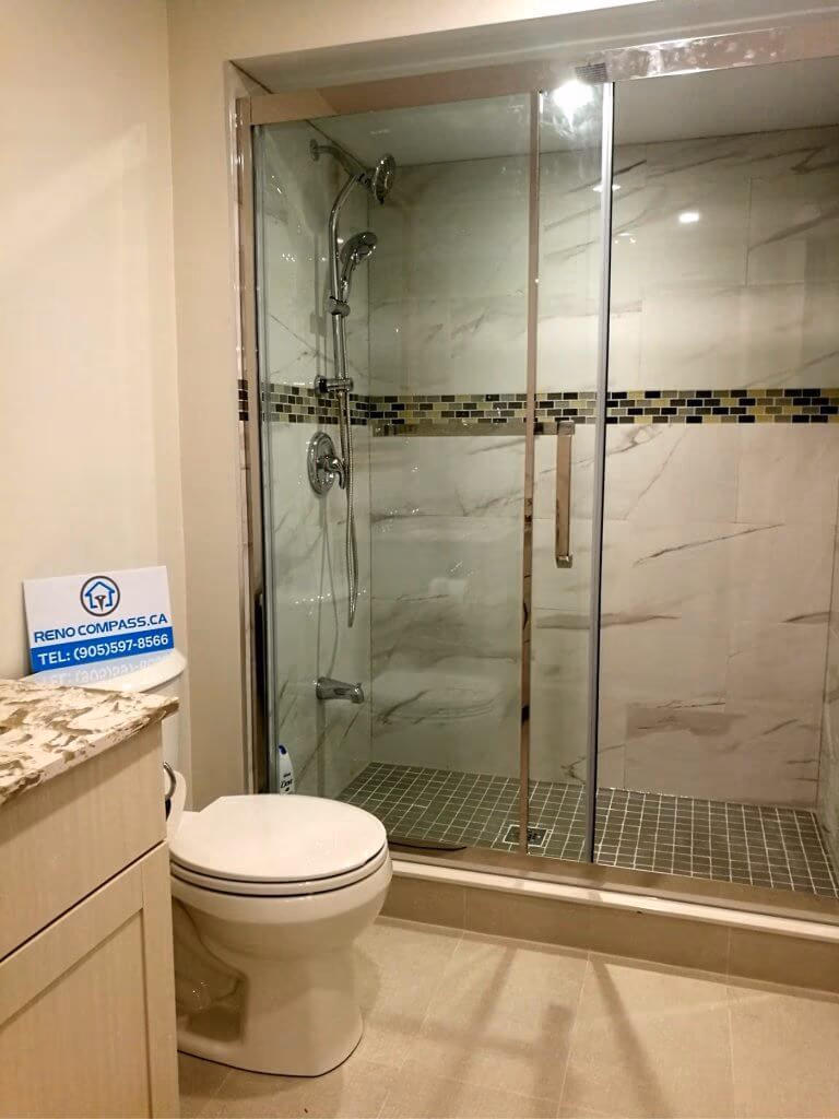 This Markham basement renovation features a fully upgraded bathroom with a sleek glass-enclosed shower and contemporary tile finishes. The space includes a walk-in shower with sliding glass doors, modern rainfall fixtures, mosaic accent tiles, and durable floor tiling designed for moisture resistance. The clean layout and neutral color palette create a bright, comfortable environment that complements the finished basement living space. Completed by a trusted Toronto renovation company, this basement bathroom renovation combines practicality, style, and long-term durability for modern family use.