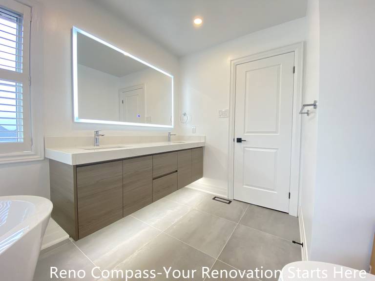 Spacious double sink bathroom vanity featured in an Oakville interior renovation, showcasing a wall-mounted wood-finish cabinet, quartz countertop, and large LED backlit mirror. The design emphasizes functionality, clean lines, and balanced lighting, delivering a modern bathroom upgrade by a professional Toronto renovation company.