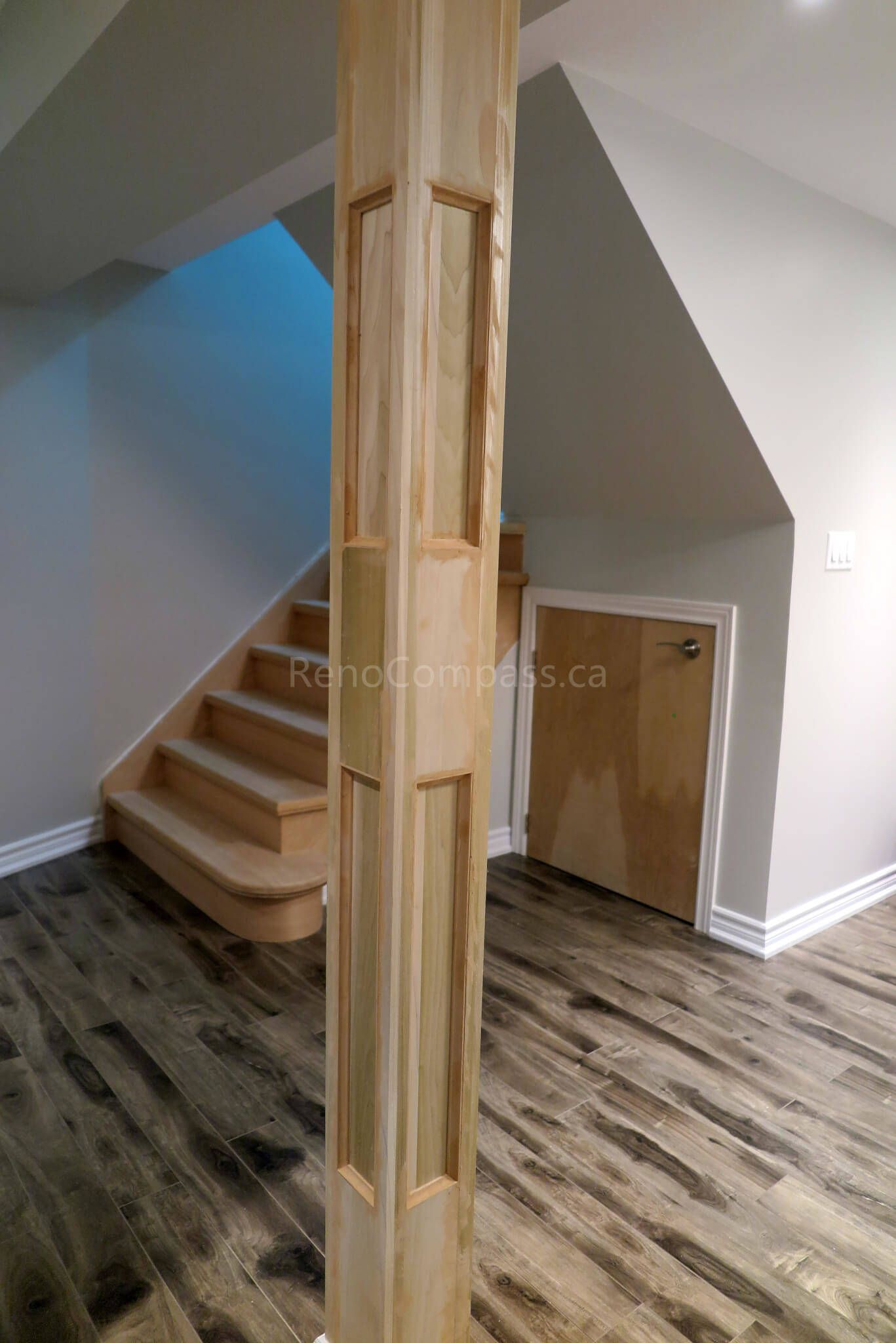 After photo from a Richmond Hill basement renovation featuring a newly built staircase with custom wood posts, modern vinyl plank flooring, and smart under-stair storage. A beautiful combination of craftsmanship and functional design in a finished basement.