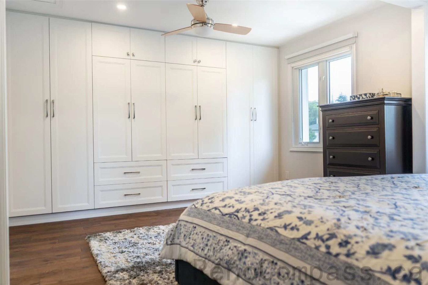 This North York interior renovation features a bright and functional bedroom upgrade with custom built-in wardrobe cabinets that maximize storage and organization. The design includes clean white cabinetry, modern hardware, warm hardwood flooring, and soft natural light from the window. Completed by a professional Toronto renovation company, this bedroom renovation blends practicality with elegant design, creating a comfortable and well-organized living space.