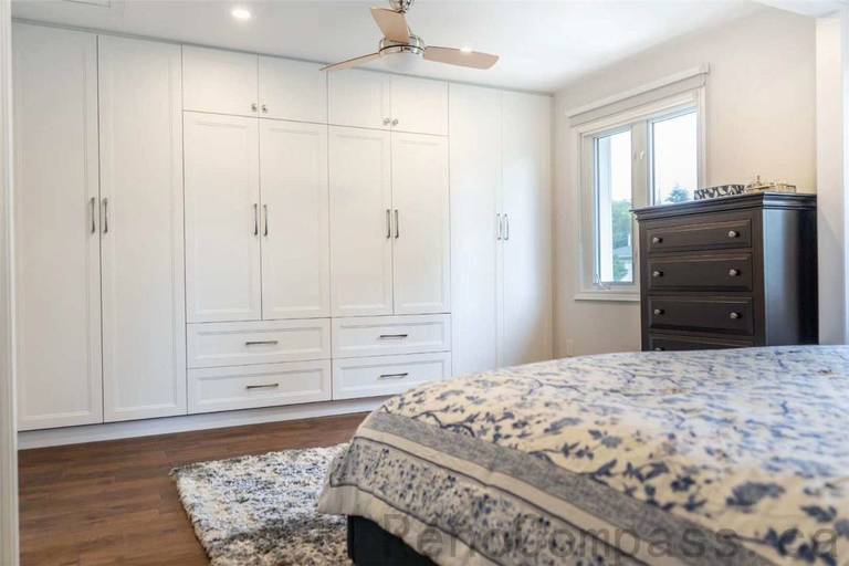 This North York interior renovation features a bright and functional bedroom upgrade with custom built-in wardrobe cabinets that maximize storage and organization. The design includes clean white cabinetry, modern hardware, warm hardwood flooring, and soft natural light from the window. Completed by a professional Toronto renovation company, this bedroom renovation blends practicality with elegant design, creating a comfortable and well-organized living space.