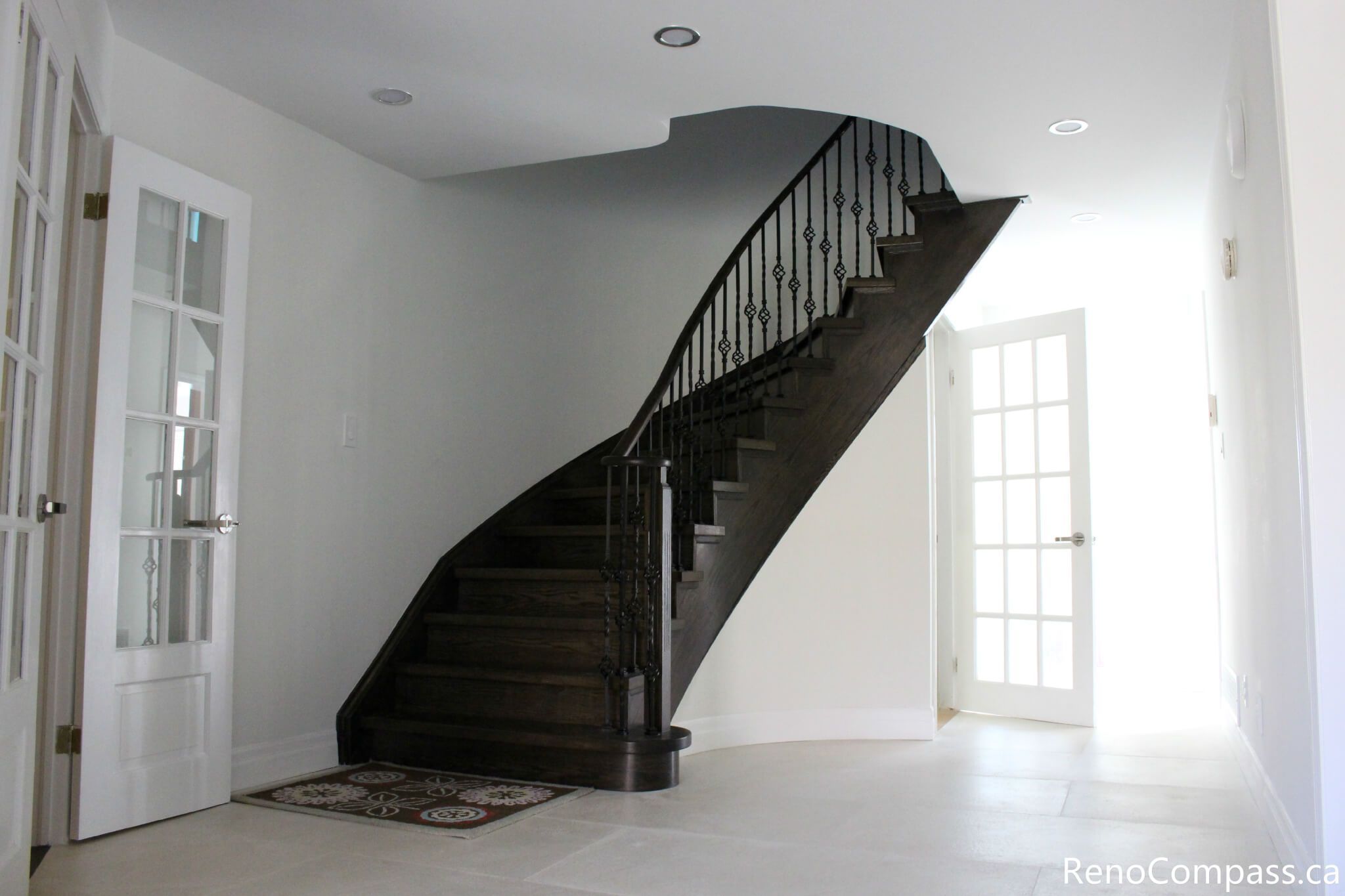 This Mississauga interior renovation features a modern staircase upgrade with dark hardwood steps, custom iron railings, and a bright open entryway design. The clean wall finishes, recessed lighting, and updated flooring enhance both functionality and visual appeal, creating a welcoming and elegant interior space. Completed by a trusted Toronto renovation company, Reno Compass Inc., this project highlights professional craftsmanship and contemporary home renovation design.