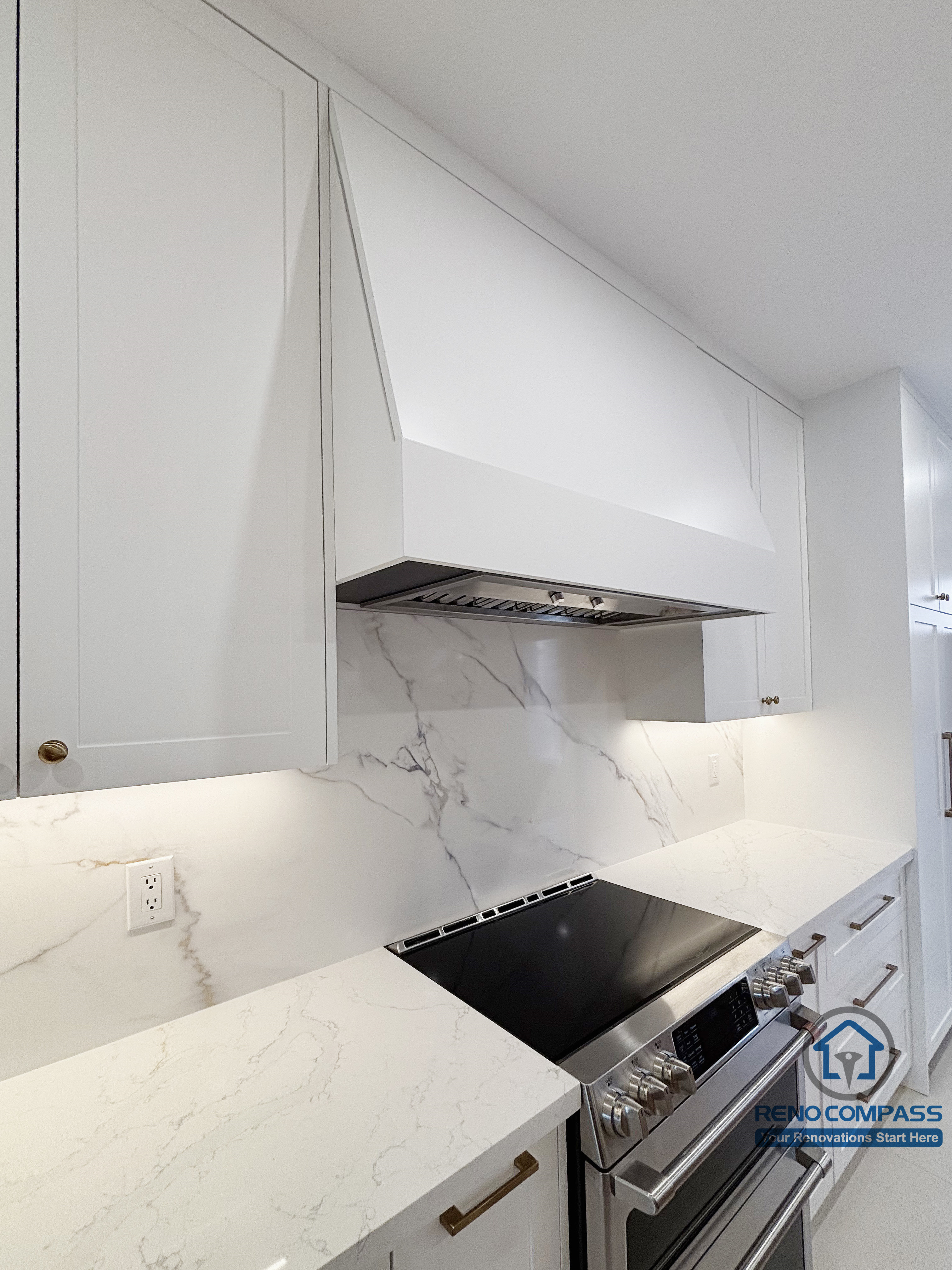 This Oakville kitchen renovation highlights the vertical composition of the main cooking area, featuring a custom hood enclosure seamlessly integrated with surrounding cabinetry. The marble-style backsplash extends cleanly behind the range, creating a continuous and refined surface that enhances both function and visual order. Careful alignment and restrained detailing reinforce a cohesive, durable cooking zone designed for long-term daily use. Completed by Reno Compass, this kitchen detail reflects precision and thoughtful execution in a modern Oakville home.