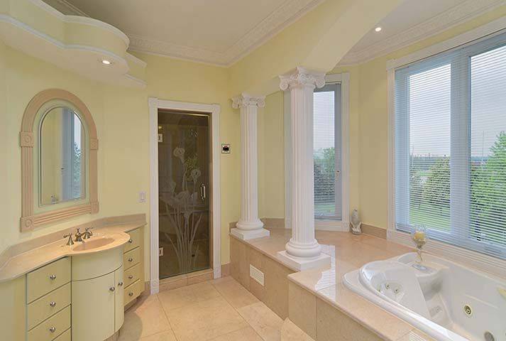 Bright luxury ensuite bathroom from a Toronto custom home renovation featuring a skylight ceiling, large soaking tub, elegant vanity, and expansive windows that bring in natural light. The spacious layout and refined architectural details create a relaxing spa-like environment within the master suite. This bathroom renovation was completed by Reno Compass, a trusted Toronto Renovation Company specializing in luxury home rebuilds and interior renovations across the Greater Toronto Area.