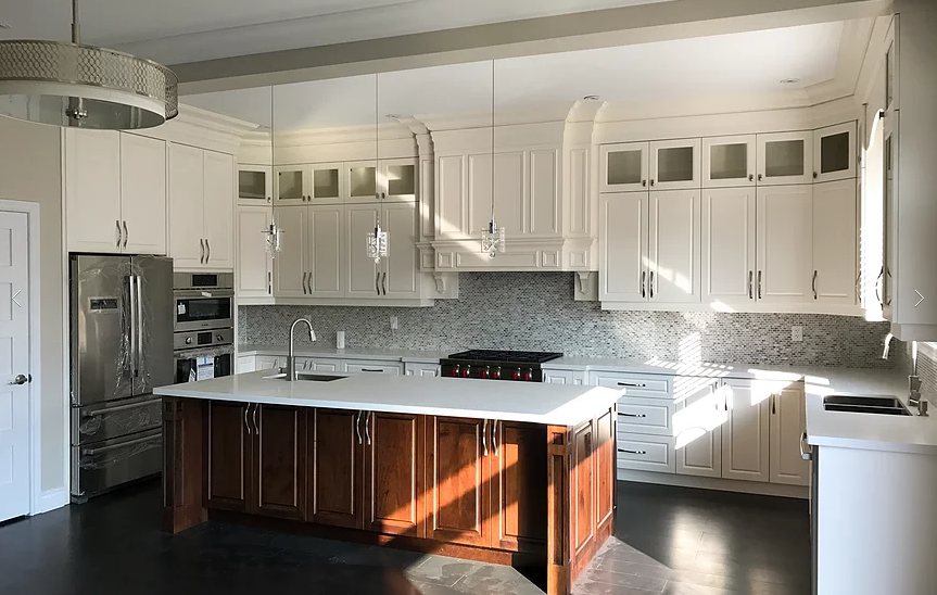 This modern Markham kitchen renovation features custom white cabinetry, a large central island with dark wood base, quartz countertops, and built-in stainless steel appliances. Elegant mosaic backsplash, detailed crown molding, and pendant lighting create a bright and luxurious cooking space. Completed by a professional Toronto renovation company, this kitchen combines functionality, storage, and timeless design for modern family living.