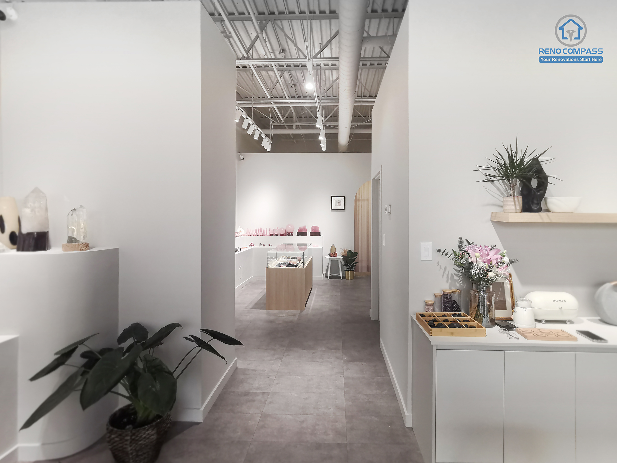 This image showcases a completed Markham crystal shop renovation featuring a clean, minimalist retail interior. The space is designed with soft neutral tones, custom display shelving, polished concrete flooring, and carefully planned lighting to highlight crystal and spiritual products. As a Toronto renovation company, Reno Compass focuses on functional layout, calm visual flow, and refined material selection to enhance customer experience in boutique retail spaces.