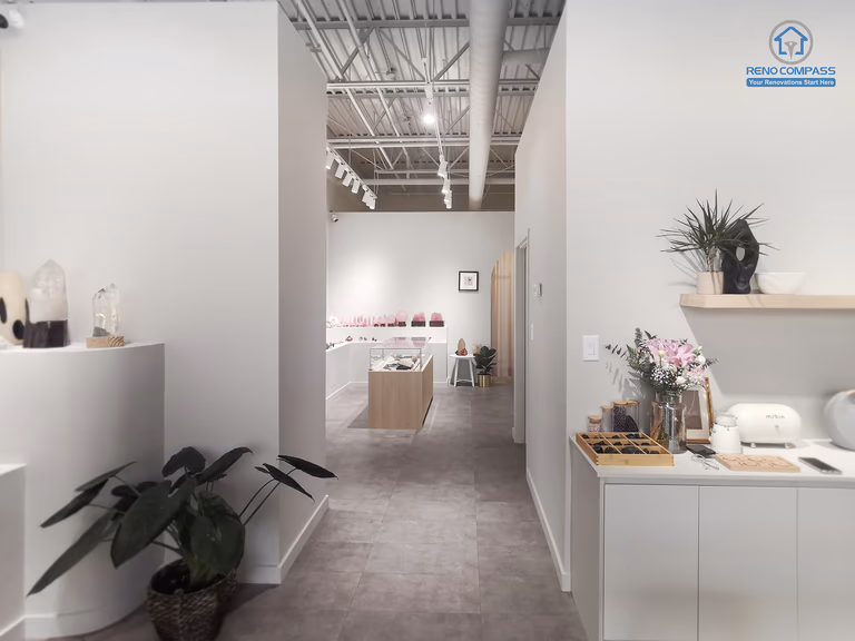 This image showcases a completed Markham crystal shop renovation featuring a clean, minimalist retail interior. The space is designed with soft neutral tones, custom display shelving, polished concrete flooring, and carefully planned lighting to highlight crystal and spiritual products. As a Toronto renovation company, Reno Compass focuses on functional layout, calm visual flow, and refined material selection to enhance customer experience in boutique retail spaces.