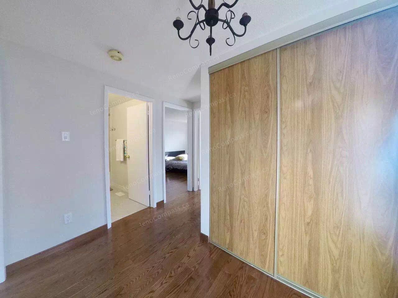 Before renovation view of a bedroom in a Scarborough home featuring original sliding closet doors, older lighting fixture, and hardwood flooring. This space was later upgraded by a professional Toronto renovation company to improve layout, lighting, and overall comfort, creating a more modern and functional bedroom environment.