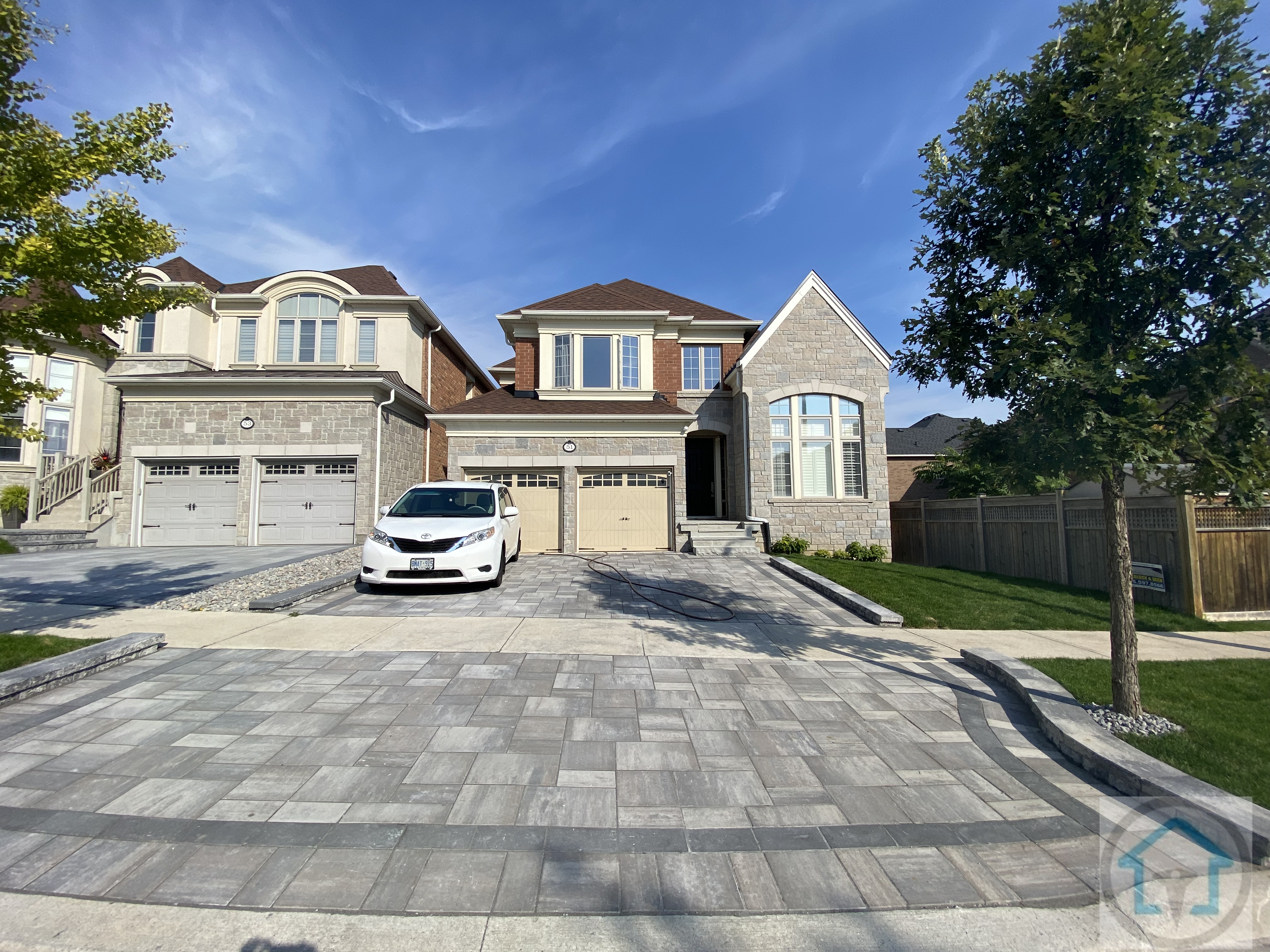 这张图片展示了位于 Richmond Hill 的独立住宅前院车道铺砖效果。车道区域采用大规格铺砖，颜色层次自然，整体铺设平整有序，与建筑立面比例协调。边缘线条清晰，行车与步行区域划分明确，在保证承重与耐用性的同时，也提升了住宅正立面的整体观感。铺砖与周围草坪、路缘及房屋外观自然衔接，使前院空间在实用性之外，兼具整洁感与高端住宅的整体质感。
