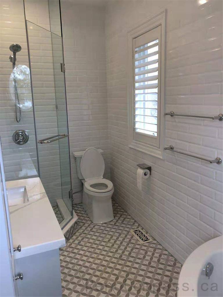 This North York bathroom renovation features a compact layout with a glass shower enclosure, classic white subway wall tiles, and patterned tile flooring. The design maximizes space efficiency while maintaining brightness and functionality, making it ideal for secondary or guest bathrooms.