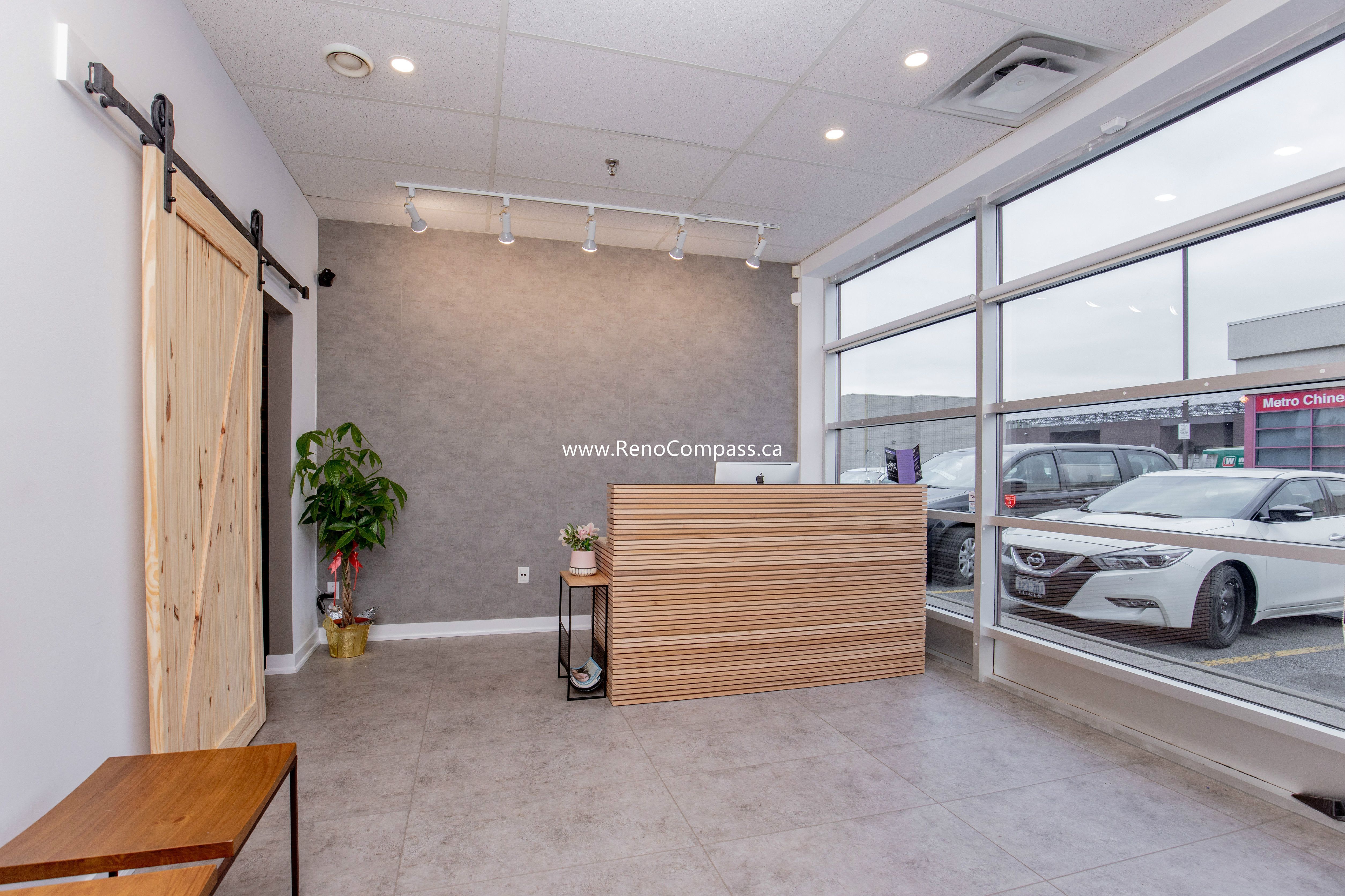 A stunning lobby renovation for The Singing School in Richmond Hill featuring a custom slatted wood reception desk, industrial barn door, and sleek large-format floor tiles. This professional commercial build-out highlights modern interior design and high-end finishes.
