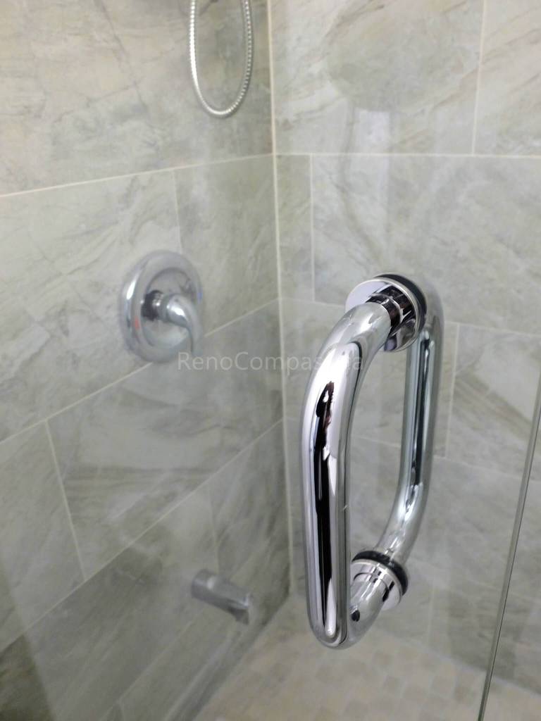 This North York bathroom renovation features a sleek glass shower door with a polished chrome handle and upgraded shower fixtures set against full-height marble-look tile walls. Completed by a professional Toronto renovation company, the project highlights precision installation, durable materials, and modern design details that enhance both functionality and overall bathroom aesthetics.
