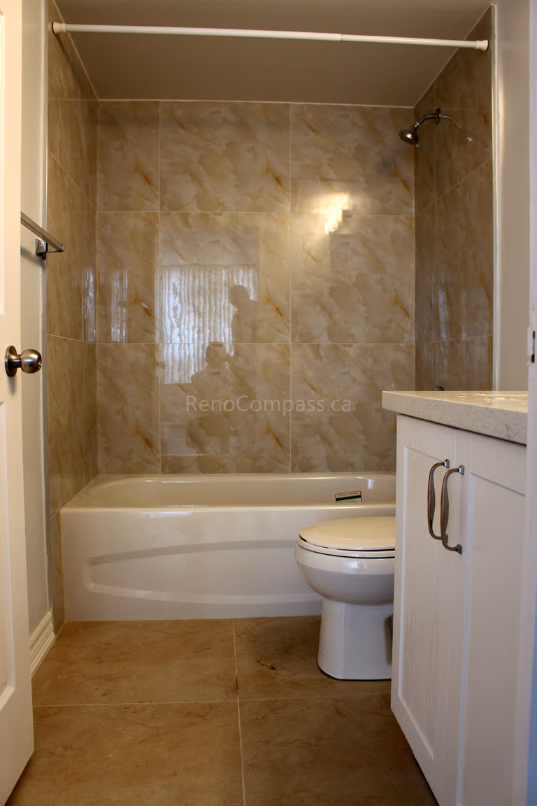 This Mississauga interior renovation project features a clean and functional bathroom upgrade with a modern bathtub, full-height marble-style wall tiles, new vanity cabinet, and upgraded flooring. Completed by Reno Compass, a professional Toronto renovation company, the design focuses on durability, easy maintenance, and practical daily use for homeowners in the GTA.