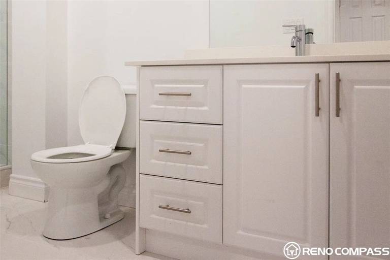 This Markham basement renovation features a bright and modern bathroom upgrade designed for comfort and practicality. The space includes a newly installed vanity with ample storage, sleek hardware, and a clean white countertop that enhances the overall brightness of the room. A modern toilet and fresh tile flooring complete the bathroom, creating a functional and low-maintenance space for everyday use. Completed by Reno Compass Inc., this basement bathroom renovation in Markham focuses on clean finishes, efficient layout, and durable materials, delivering a refreshed and contemporary lower-level living environment.