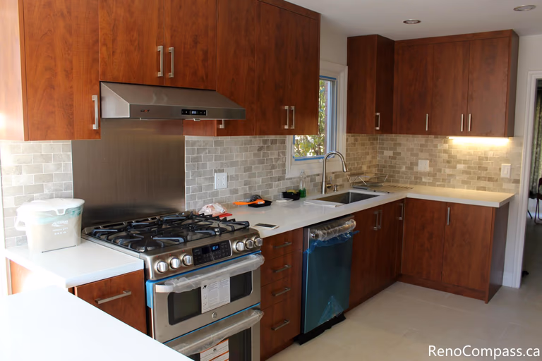This modern kitchen is part of a full house renovation project in Mississauga completed by a professional Toronto renovation team. The space features rich wood cabinetry, quartz countertops, a contemporary backsplash, and stainless steel appliances, creating a warm yet modern cooking environment. The renovation focused on improving functionality, storage efficiency, and overall home value while delivering a clean and timeless kitchen design suitable for everyday family living.