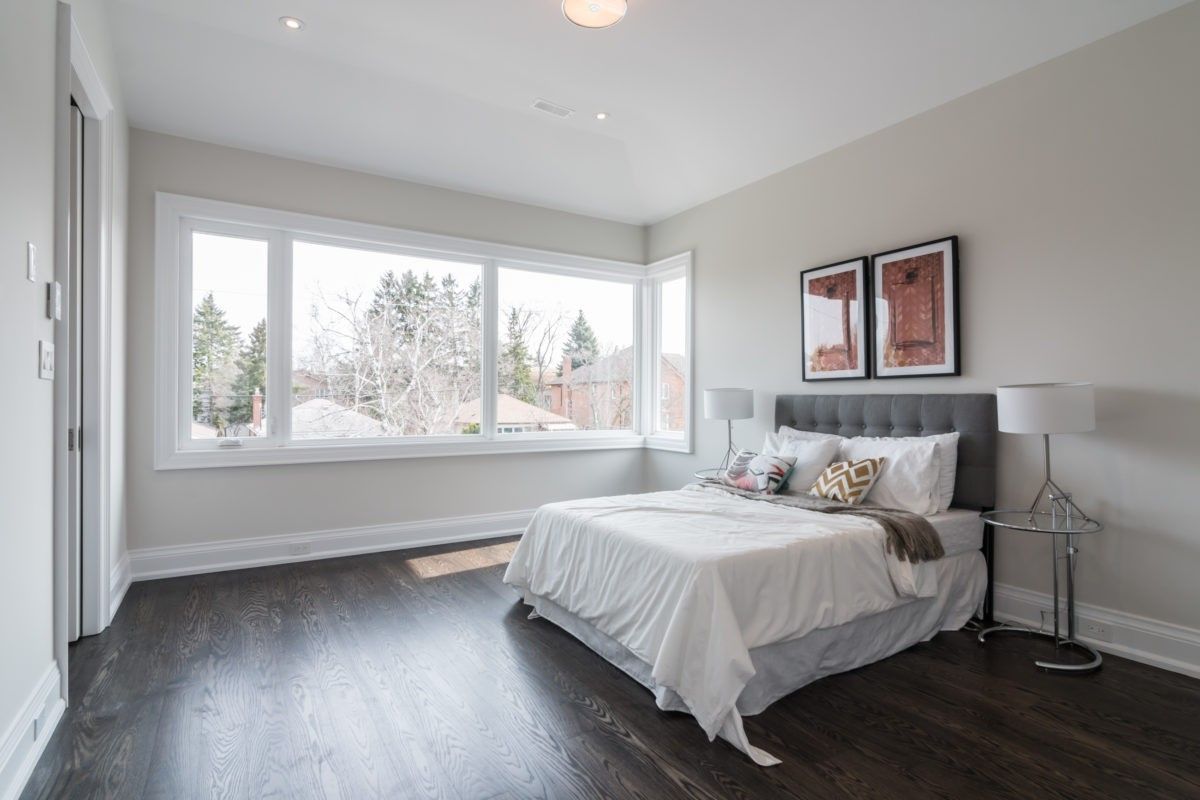This elegant bedroom is part of a 4,500 sq ft modern home renovation in Toronto, designed to maximize natural light and comfort. Expansive corner windows brighten the space while dark hardwood flooring and soft neutral tones create a calm and contemporary atmosphere. The refined layout enhances both functionality and visual openness, reflecting the quality craftsmanship of a professional Toronto Renovation Company, Reno Compass Inc. This project highlights modern residential design tailored for luxury living.