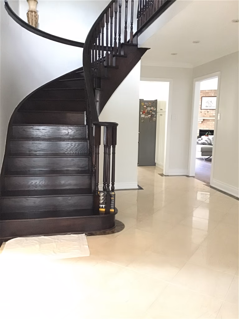 Transform your foyer with our professional staircase staining services. Our team updated this elegant curved staircase with a modern dark wood finish, providing a sophisticated contrast to the bright, open-concept home.