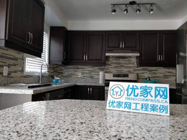 This kitchen renovation project in Ajax showcases a modern upgrade featuring dark wood cabinetry, granite countertops, and a contemporary mosaic backsplash. The layout enhances both functionality and aesthetics, with improved lighting and efficient use of space. As part of a full interior and exterior house renovation, this kitchen reflects high-quality craftsmanship and practical design solutions for everyday living.