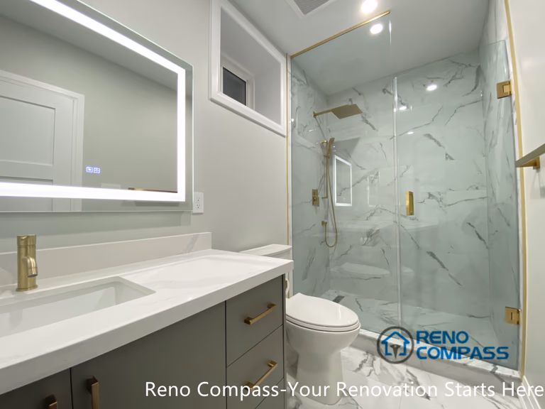 This Newmarket basement bathroom renovation features a modern walk-in glass shower with marble-look porcelain tiles, brushed gold fixtures, and a custom vanity with an LED backlit mirror. Designed and built by a professional Toronto renovation company, the space maximizes brightness, functionality, and visual cleanliness, creating a comfortable and elegant basement bathroom suitable for daily use or guest accommodation.