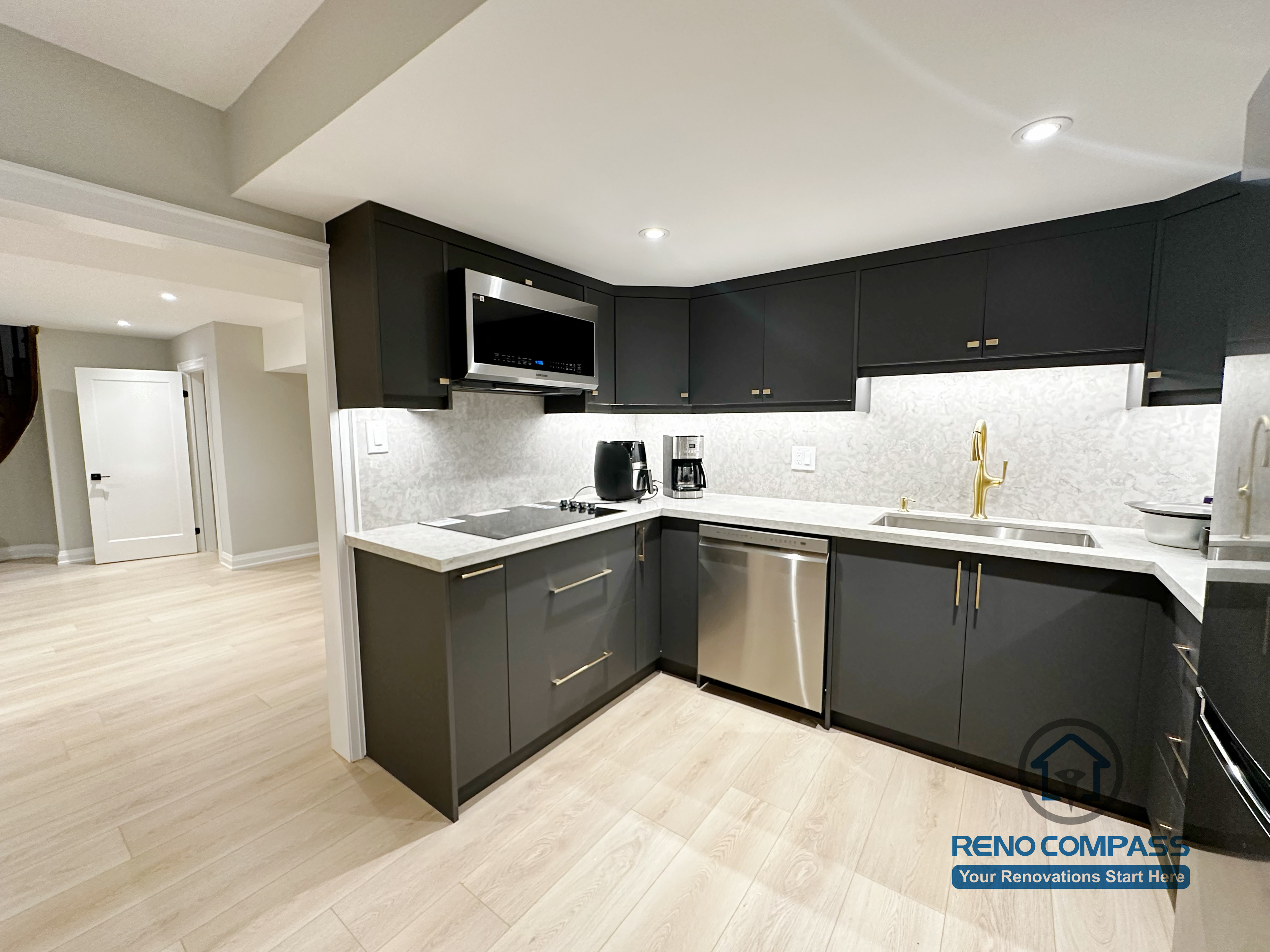 Basement renovation in Richmond Hill featuring a modern kitchenette with matte black cabinetry, stainless steel appliances, quartz-style countertops, and efficient space planning for daily use.