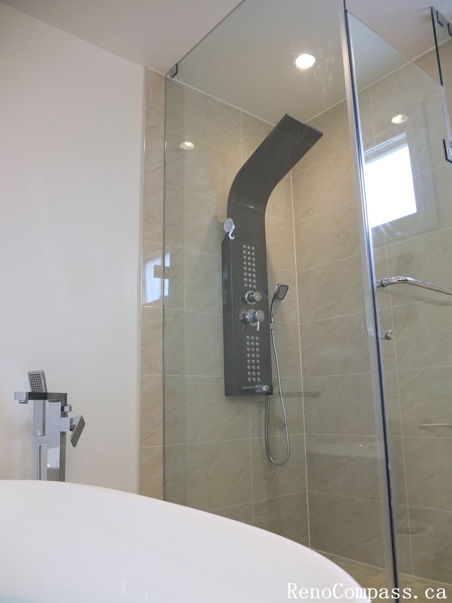 Interior bathroom renovation in North York featuring a frameless glass shower, full-body rain shower system, and large-format porcelain wall tiles. This Toronto interior renovation focuses on modern functionality, clean detailing, and efficient use of space for everyday comfort.