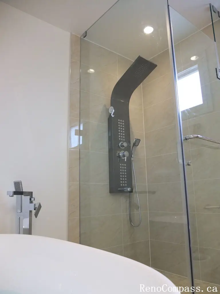 Interior bathroom renovation in North York featuring a frameless glass shower, full-body rain shower system, and large-format porcelain wall tiles. This Toronto interior renovation focuses on modern functionality, clean detailing, and efficient use of space for everyday comfort.