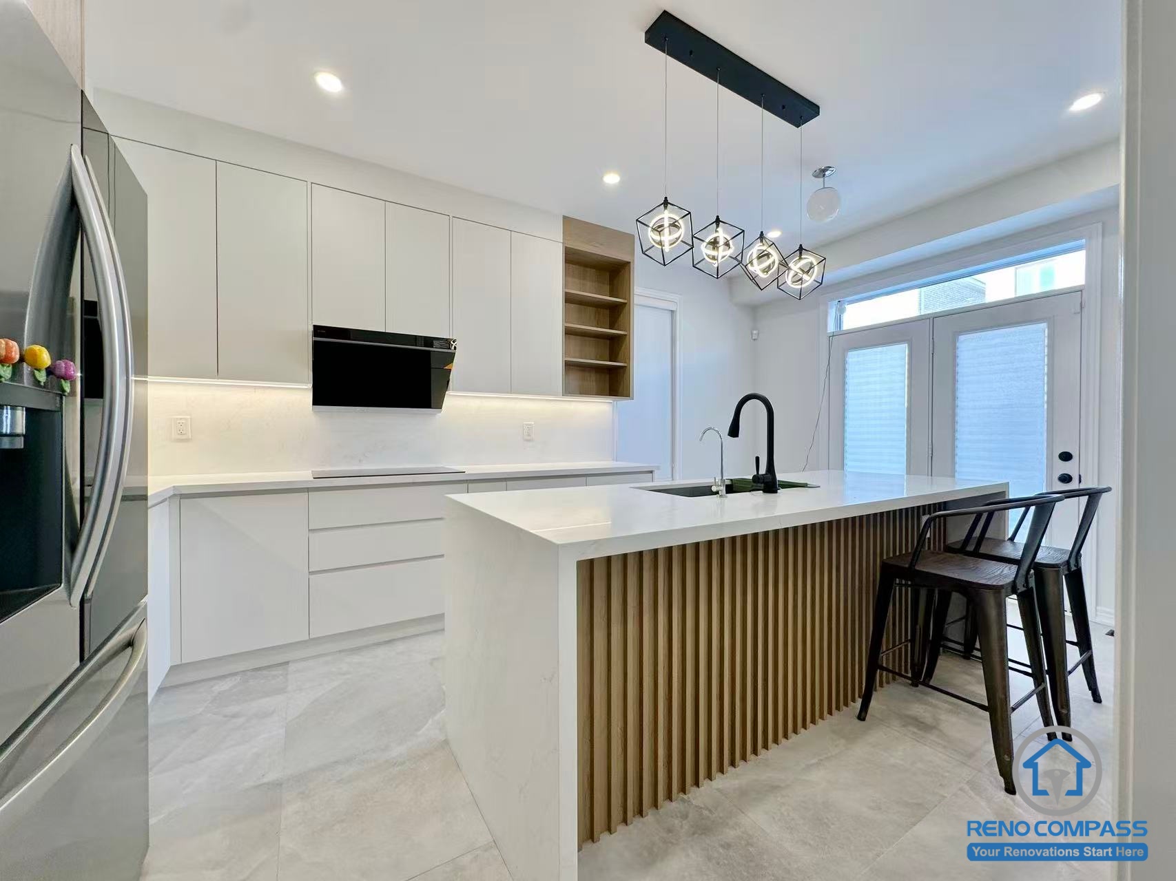 This Stouffville kitchen renovation showcases a contemporary island design featuring vertical wood panel detailing, a quartz countertop, and a matte black sink and faucet. Modern pendant lighting and full-height cabinetry create a bright, open-concept cooking and dining space. Completed by a reliable Toronto renovation company, Reno Compass Inc., this project highlights refined material selection and modern kitchen craftsmanship.