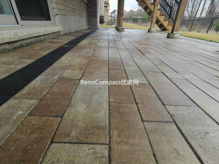 Professional interlocking patio installation in Aurora featuring durable stone pavers and clean border detailing beneath an elevated deck. This custom outdoor renovation improves drainage, usability, and backyard aesthetics while creating a functional covered patio space for all-season outdoor living.
