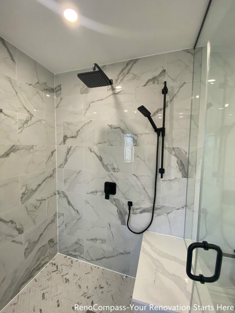 This Thornhill bathroom renovation showcases a detailed walk-in shower interior finished with marble-look porcelain wall tiles and a textured shower base. Matte black rain shower and handheld fixtures create a bold contrast against the light stone surfaces, adding a modern and refined aesthetic. The frameless glass enclosure enhances brightness and visual openness, while the carefully selected materials ensure durability, easy maintenance, and long-term daily comfort.