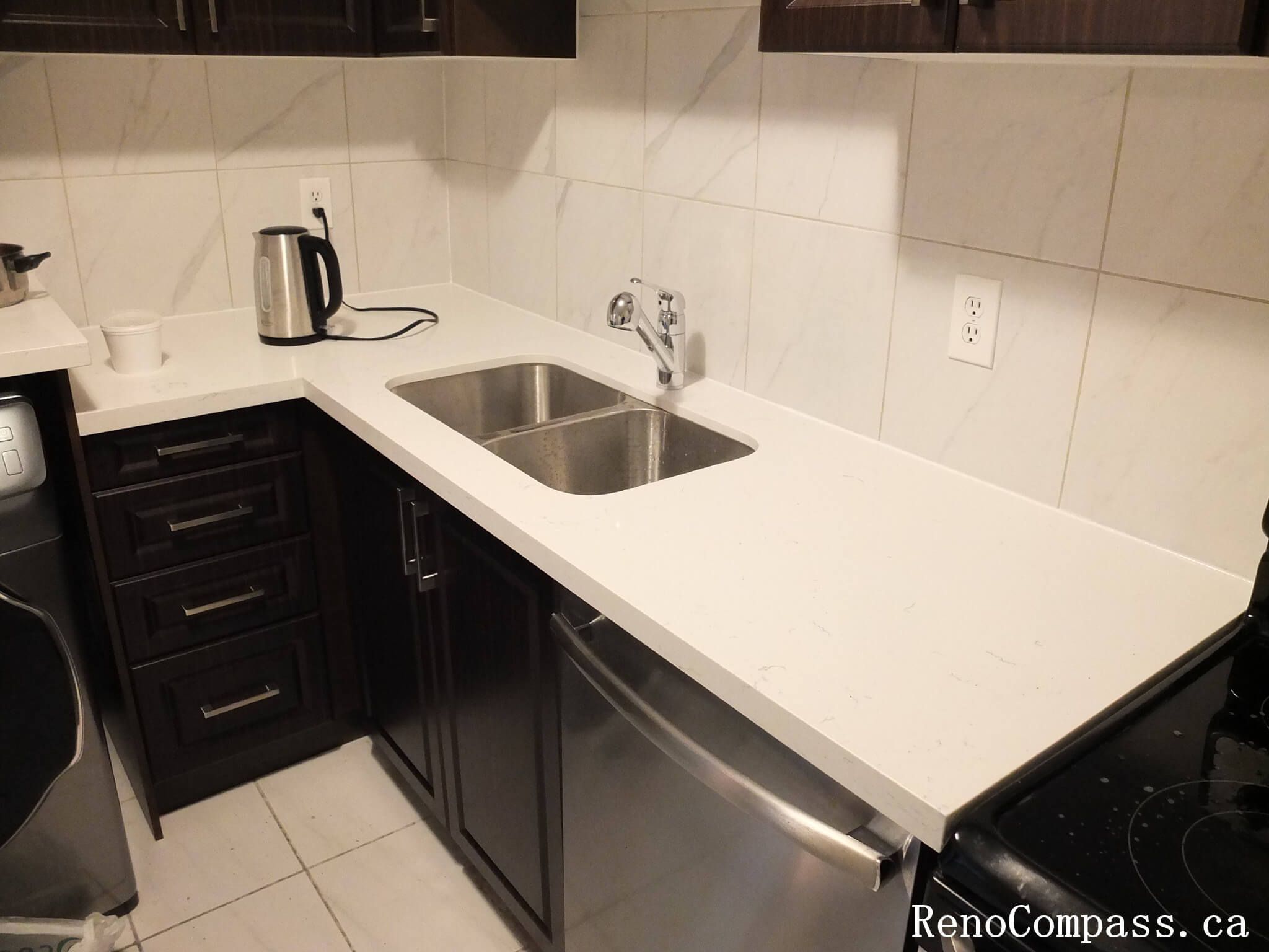 A smart L-shaped kitchen design that optimizes workflow and storage. Featuring custom espresso cabinetry, integrated stainless steel appliances, and premium white quartz countertops in a professional Mississauga renovation.