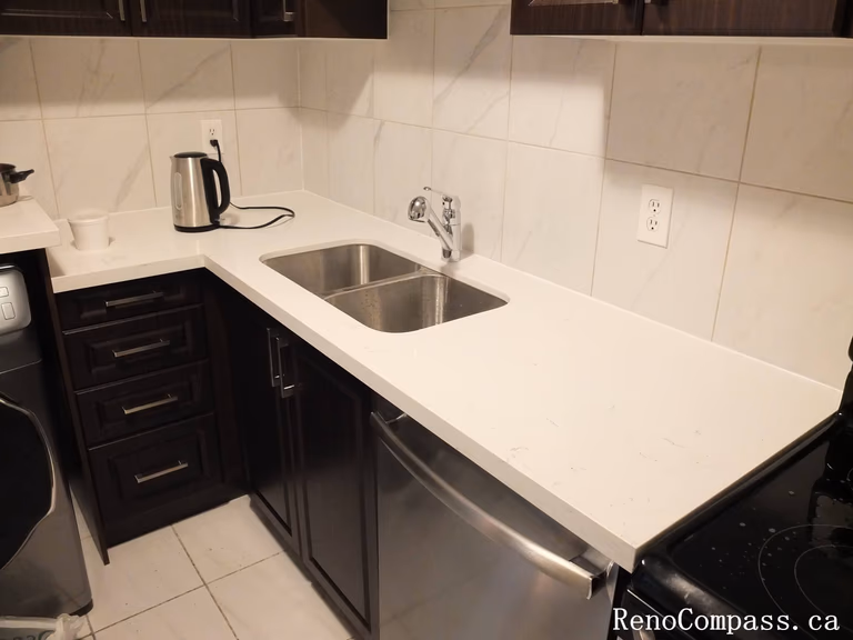A smart L-shaped kitchen design that optimizes workflow and storage. Featuring custom espresso cabinetry, integrated stainless steel appliances, and premium white quartz countertops in a professional Mississauga renovation.