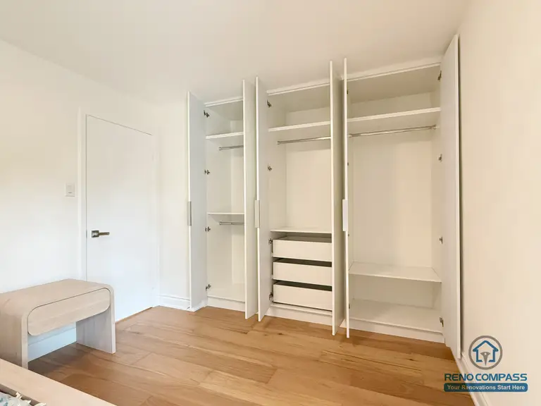 A custom-built open closet system featuring adjustable shelves, double hanging space, and soft-closing drawers. The clean white finish pairs beautifully with the warm hardwood flooring, creating a functional and modern bedroom storage upgrade. Completed in North York by Reno Compass.
定制开放式衣柜系统，包含可调节层板、双挂衣区与缓冲抽屉设计。白色柜体与暖色木地板相搭配，让卧室收纳更实用、更现代。本项目由 Reno Compass 在北约克完成。
