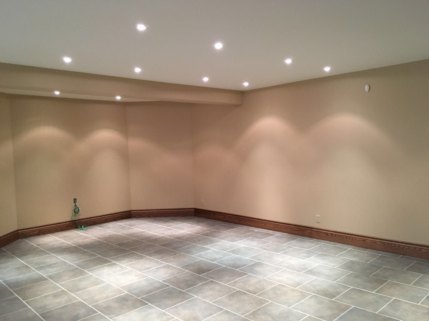 This Toronto interior renovation showcases a newly finished basement designed for flexibility and modern living. The space features durable large-format tile flooring, warm neutral wall tones, and evenly spaced recessed pot lights that create a bright and inviting atmosphere. Clean baseboard detailing and an open layout allow the basement to be used as a recreation room, home theatre, or additional living space. Completed by a professional Toronto renovation company, this basement renovation combines practicality, comfort, and contemporary interior design.