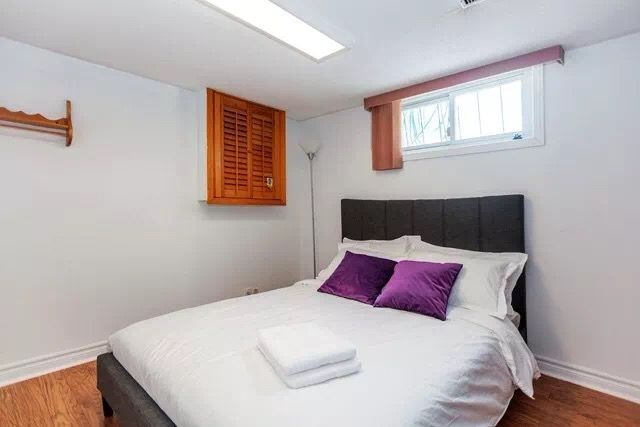This Toronto interior renovation features a simple and comfortable basement bedroom with clean white walls, modern flooring, and a cozy bed setup. The space is designed to maximize comfort and functionality while maintaining a bright and organized atmosphere. This renovation creates a practical guest or rental bedroom suitable for modern Toronto home living.