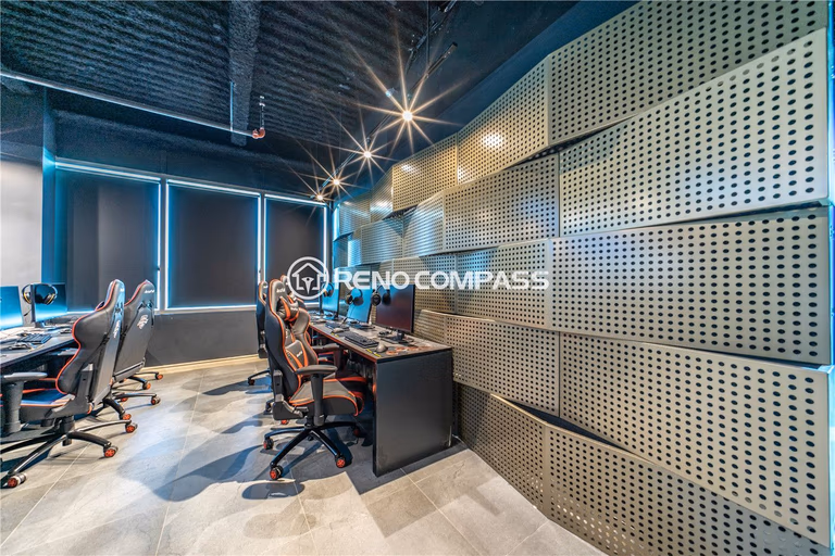Professional internet cafe gaming room renovation in Markham featuring custom gaming desk installation, ergonomic gaming chairs, acoustic wall panels, and modern LED lighting design. This commercial gaming cafe construction project highlights organized wiring systems, durable tile flooring, and contemporary industrial ceiling finishes, creating an immersive and comfortable gaming environment by experienced Toronto renovation contractor Reno Compass Inc.
