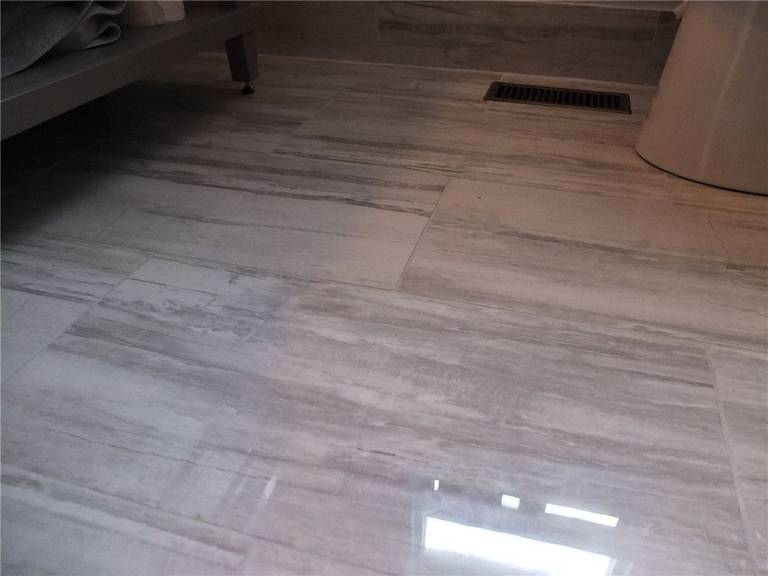 This bathroom renovation detail highlights the installation of large-format tile flooring with a clean grout layout and integrated floor drain. The neutral-toned tiles enhance visual continuity while improving water resistance and ease of maintenance. Precise alignment around fixtures ensures a polished finish and long-term durability. Completed by a professional Toronto renovation company, this flooring upgrade emphasizes workmanship quality and practical performance.