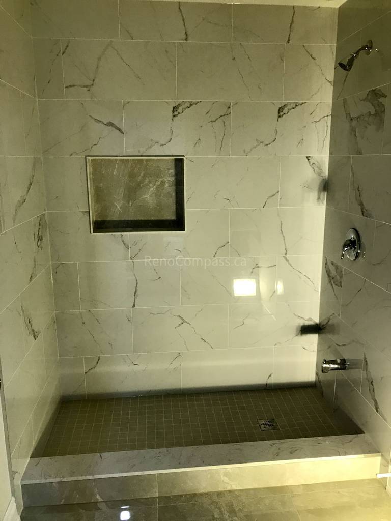 This Toronto bathroom renovation by Reno Compass features a custom walk-in shower finished with marble-look wall tiles and a built-in storage niche for everyday convenience. The raised shower base and textured floor tiles improve safety and drainage, while modern fixtures and clean tile lines create a luxurious, spa-like atmosphere. Designed for durability and comfort, this contemporary shower upgrade enhances both functionality and home value.