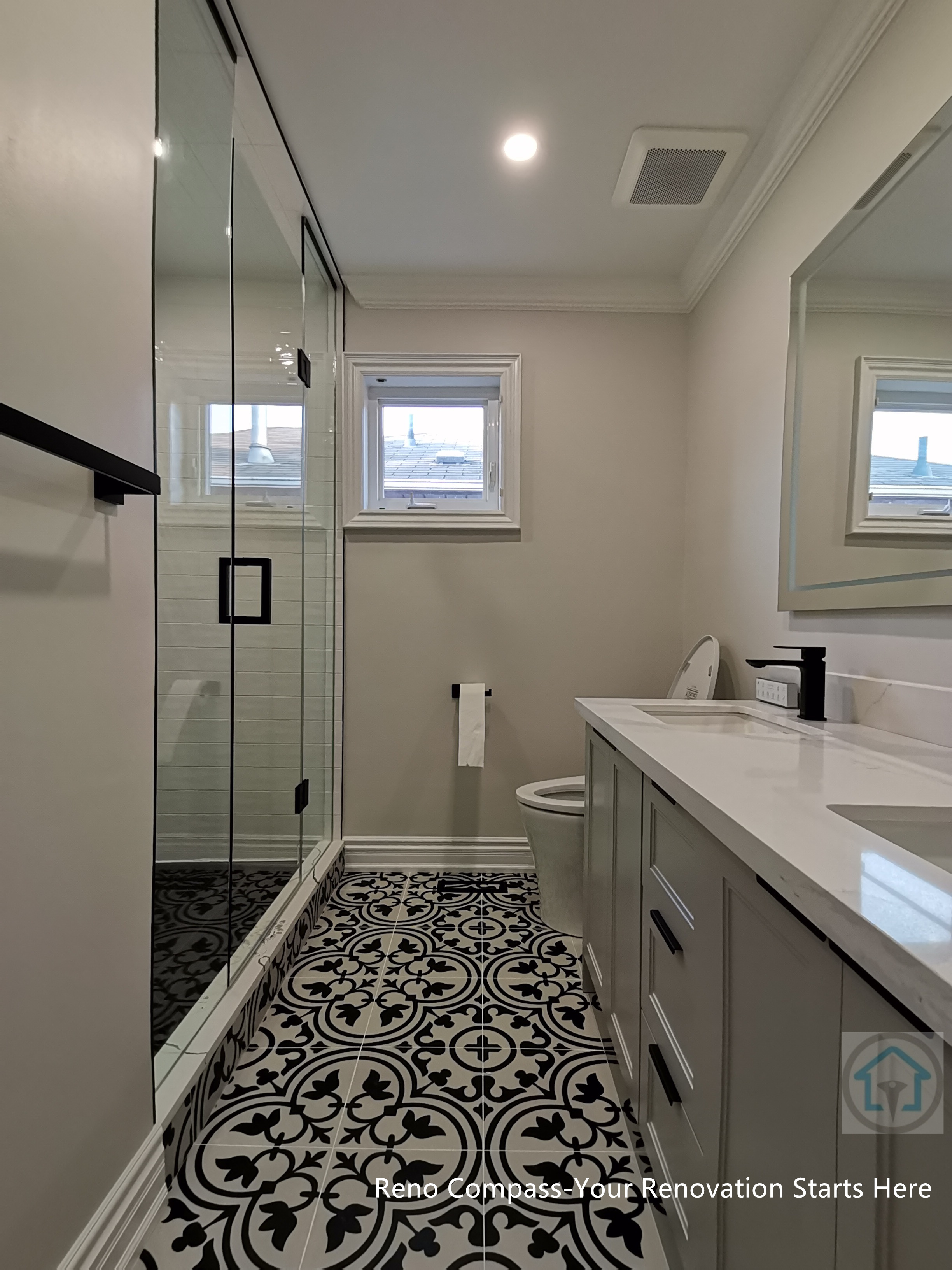 This Thornhill bathroom renovation showcases a narrow layout designed for efficiency and visual continuity. The space features a glass-enclosed shower, custom vanity with quartz countertop, matte black fixtures, and a bold patterned tile floor that adds character while maintaining a clean, modern aesthetic.