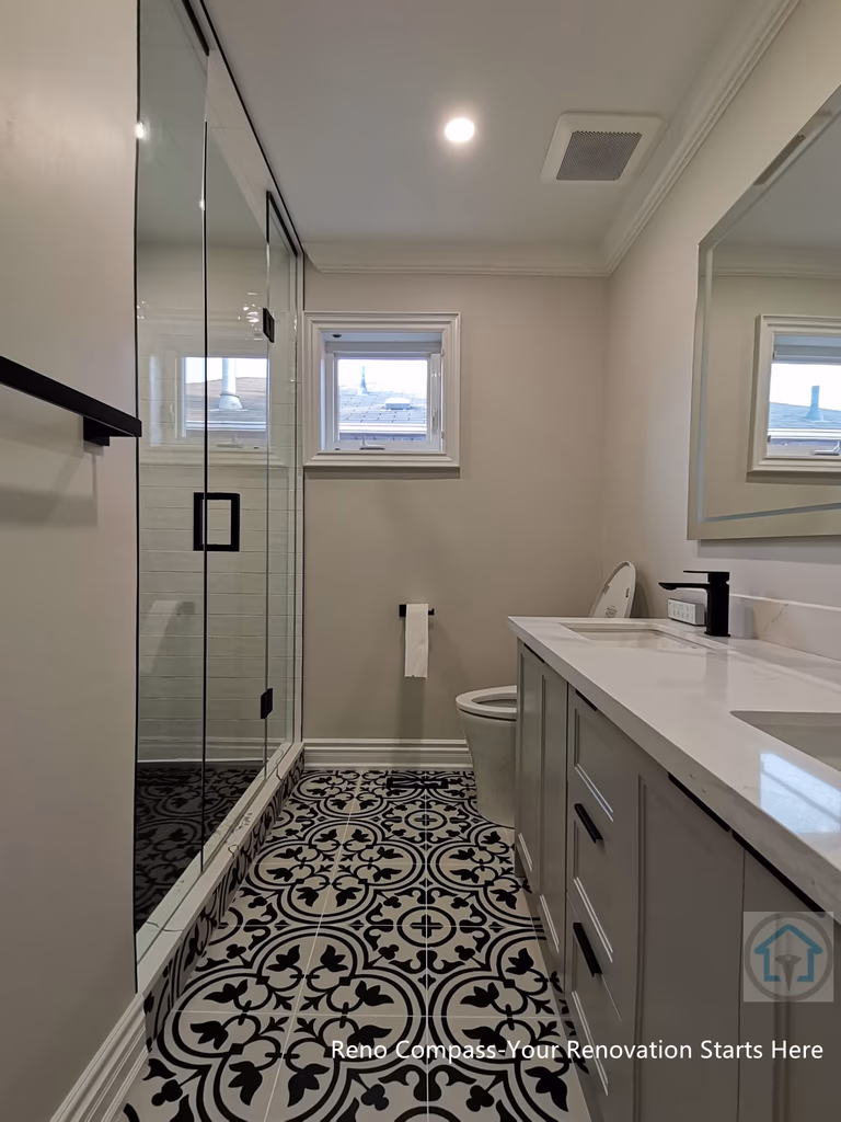 This Thornhill bathroom renovation showcases a narrow layout designed for efficiency and visual continuity. The space features a glass-enclosed shower, custom vanity with quartz countertop, matte black fixtures, and a bold patterned tile floor that adds character while maintaining a clean, modern aesthetic.