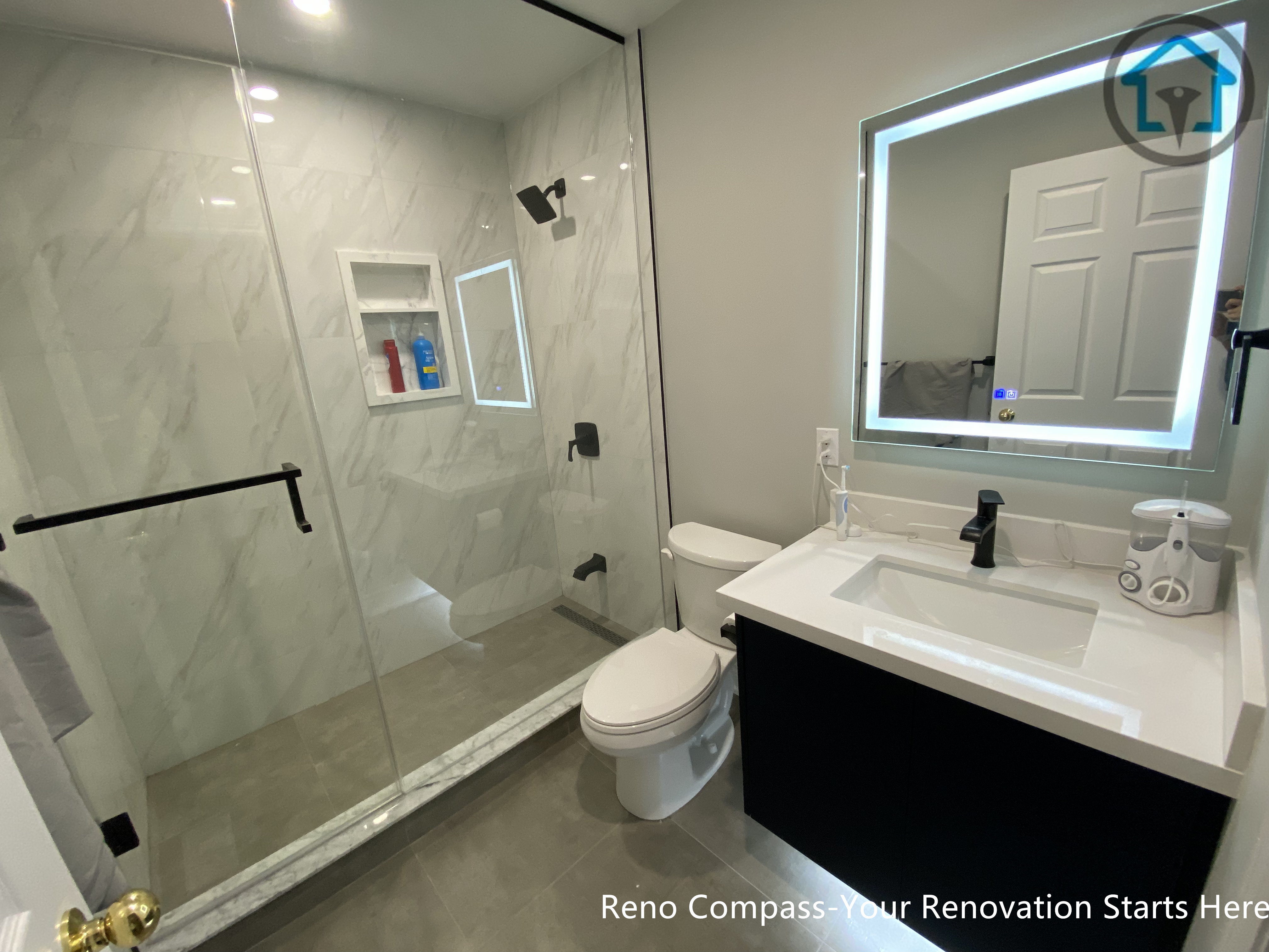 A modern basement bathroom renovation in Markham featuring a glass walk-in shower, large-format wall tiles, LED mirror, and a sleek vanity, designed for durability, comfort, and everyday use.